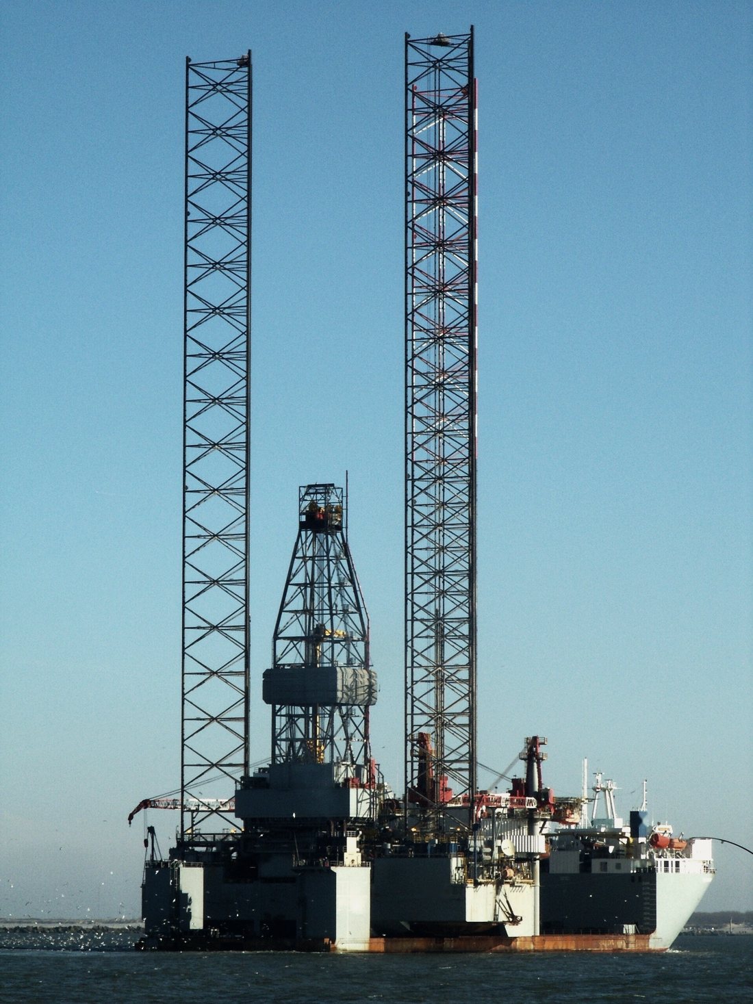 The lattice legs of a jack-up rig rising above the deck of the vessel that carries it