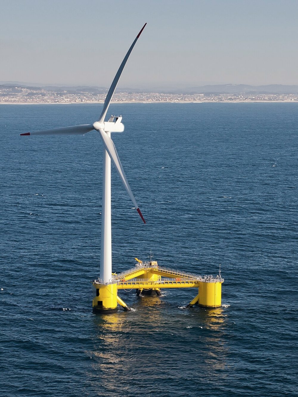 A floating wind turbine on a yellow semi-submersible foundation at sea