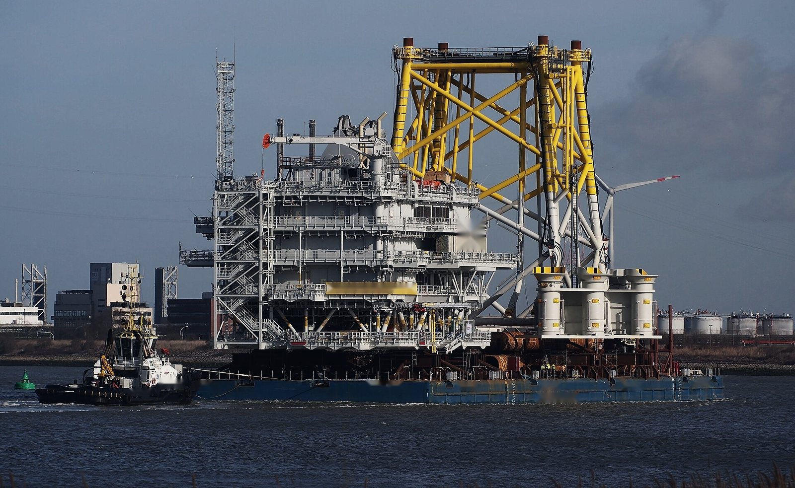 An offshore substation topside and its yellow jacket foundation on a large deck barge under tow