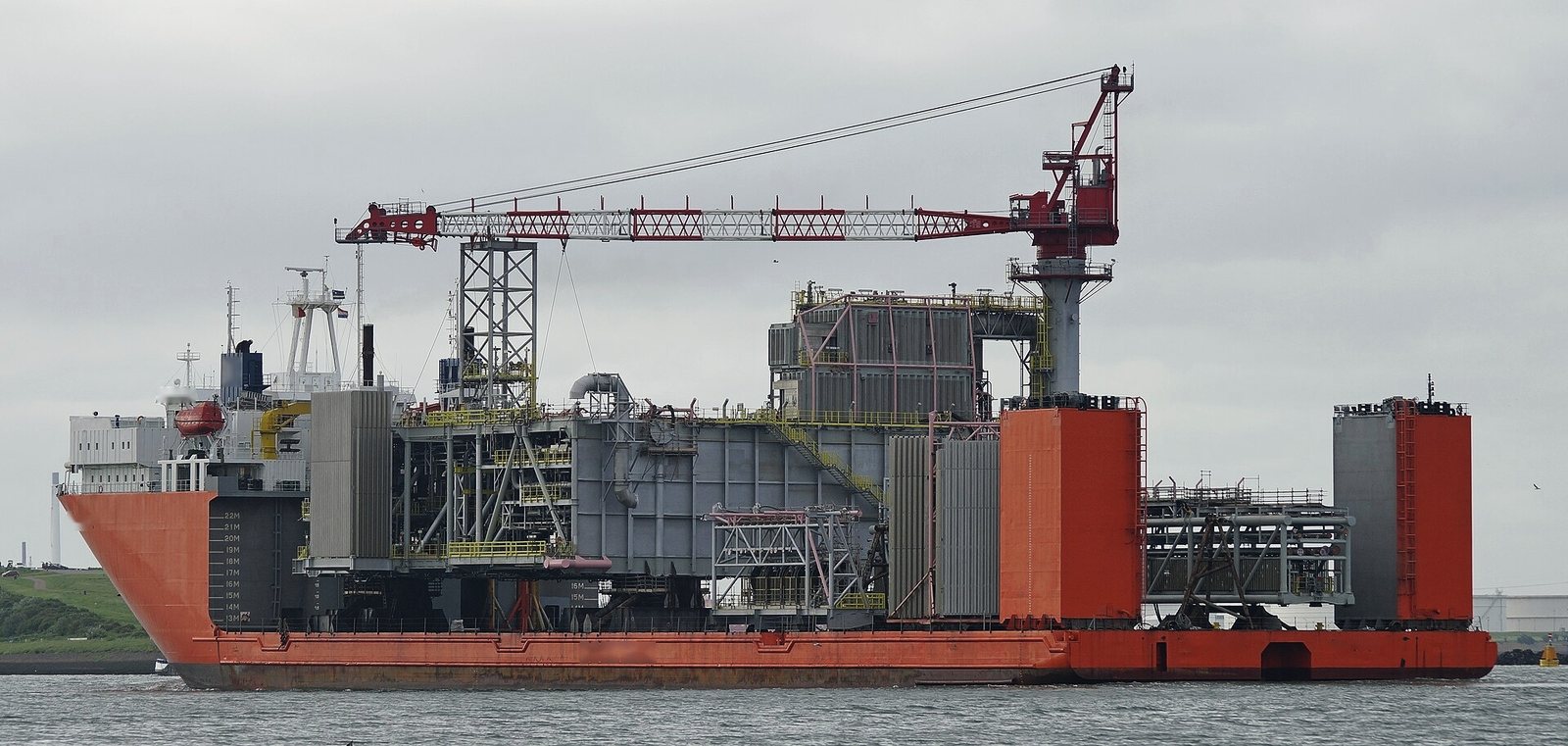 An integrated process module sitting on the open deck of a semi-submersible heavy transport vessel